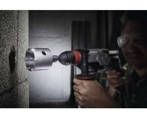 Mann bohrt mit einer Bohrkrone ein Loch in eine Wand.