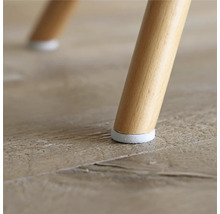 Vue détaillée d'un pied de chaise avec protection de sol sur un plancher en bois.