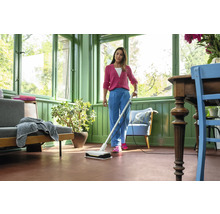 Une femme nettoie le sol avec une serpillière électrique dans une pièce lumineuse