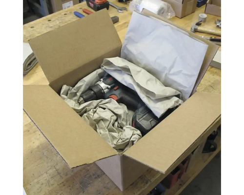 Perceuse-visseuse sans fil dans une boîte en carton ouverte avec du matériel d'emballage