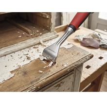 Racloir à bois en train d'enlever de la peinture d'un meuble en bois