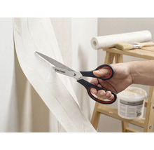 Une personne coupe du papier peint avec des ciseaux de la marque Rautner