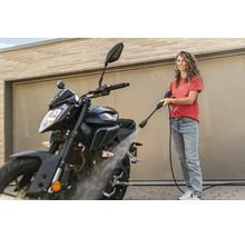 Frau reinigt Motorrad mit Hochdruckreiniger