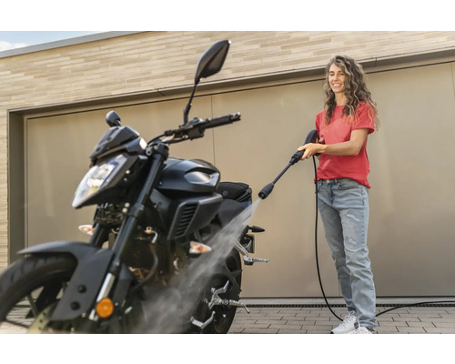 Frau reinigt Motorrad mit Hochdruckreiniger