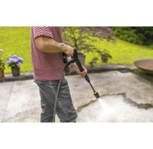 Eine Person reinigt eine Terrasse mit einem Hochdruckreiniger.