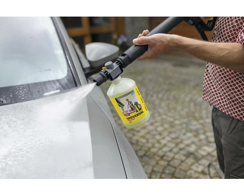Ein Mann reinigt ein Auto mit einem Hochdruckreiniger und Universalreiniger von Kärcher