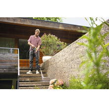 Ein Mann reinigt eine Treppe mit einem Hochdruckreiniger vor einem Wohnhaus.