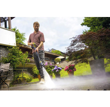 Mann reinigt mit einem Hochdruckreiniger eine Terrasse.