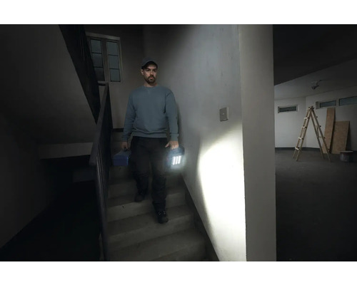 Mann geht Treppe runter mit Werkzeugkoffer und Arbeitsleuchte in der Hand