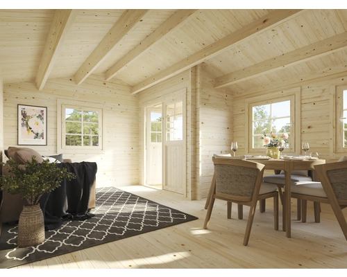 Cabane en bois claire avec coin salon et salle à manger, aménagée avec un canapé, un tapis, une table à manger et des chaises.