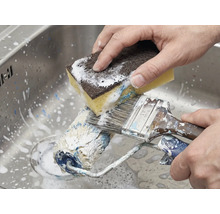 Nettoyage d'un rouleau à peinture et d'un pinceau avec une éponge dans l'évier.