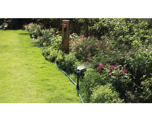 Gartenbewässerung mit Rasensprenger in einem blühenden Garten.