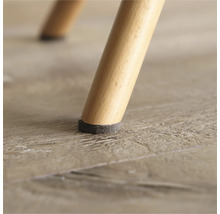 Vue détaillée d'un pied de chaise avec patin en feutre sur un plancher en bois