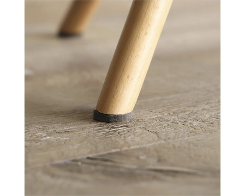 Vue détaillée d'un pied de chaise avec patin en feutre sur un plancher en bois