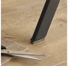 Patins en feutre sur un pied de chaise avec des ciseaux et un morceau de feutre sur le sol