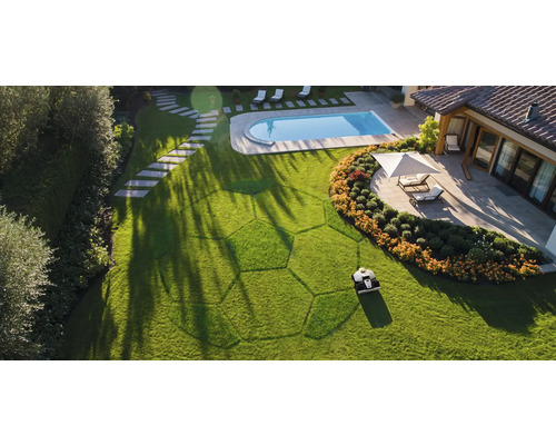 Vue de dessus : robot tondeuse coupant la pelouse dans un jardin avec piscine et terrasse.