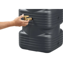 Eine Hand schraubt einen Auslaufhahn aus Messing in einen Regenspeicher aus Kunststoff.