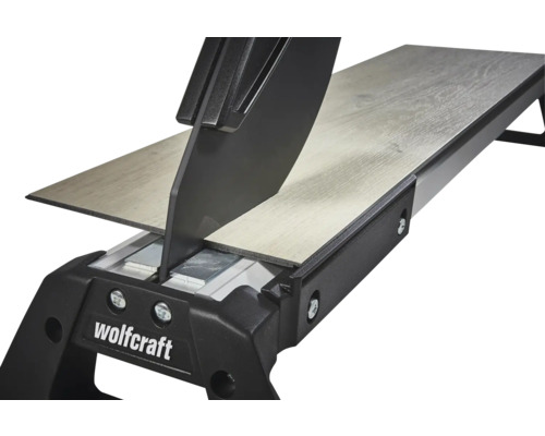 Coupe-stratifié Wolfcraft coupant une lame de stratifié avec structure en bois. Vue détaillée du mécanisme de coupe.