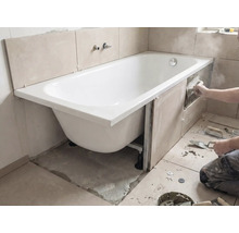 Installation d'une baignoire avec carrelage sur les murs et outils dans la salle de bains.