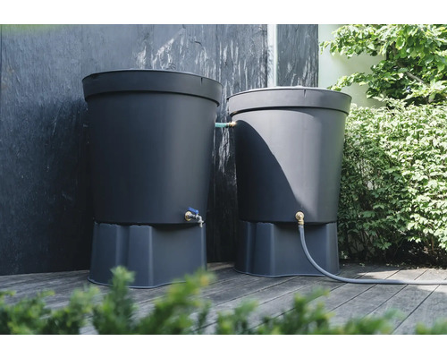 Deux réservoirs d'eau de pluie gris sur une terrasse en bois avec raccord pour tuyau d'arrosage et robinet.