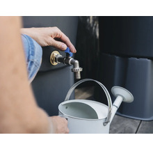 Une personne remplit un arrosoir à partir d'un robinet de récupérateur d'eau de pluie