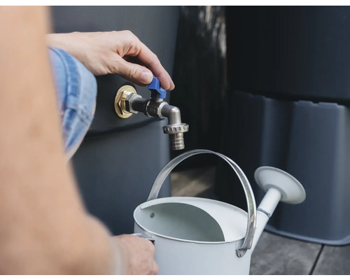 Une personne remplit un arrosoir à partir d'un robinet de récupérateur d'eau de pluie