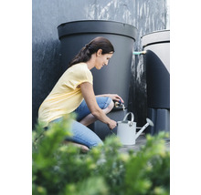 Femme remplissant un arrosoir avec de l'eau d'un récupérateur d'eau de pluie