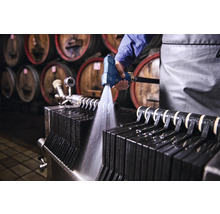 Nettoyage d'un filtre à plaques avec un pistolet pulvérisateur dans une cave à vin.