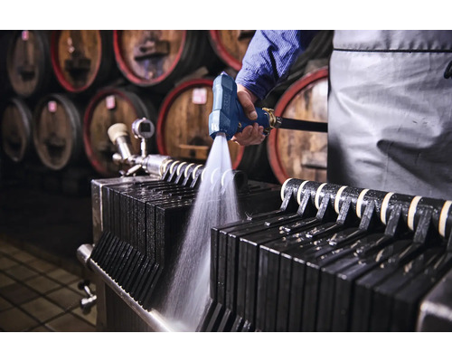 Nettoyage d'un filtre à plaques avec un pistolet pulvérisateur dans une cave à vin.