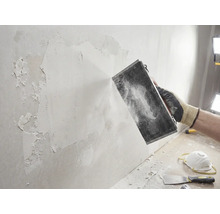 Artisan ponçant un mur avec un outil de ponçage. Projet de bricolage pour la rénovation des murs.