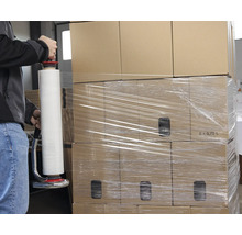 Une personne emballe des cartons avec un dévidoir de film étirable.