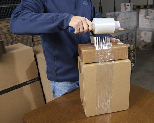Homme emballant des cartons avec du film étirable