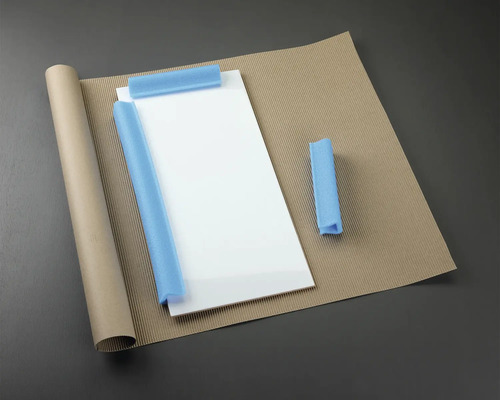 Matériaux d'emballage : plaque de verre, rouleau de papier, carton ondulé et protection en mousse.