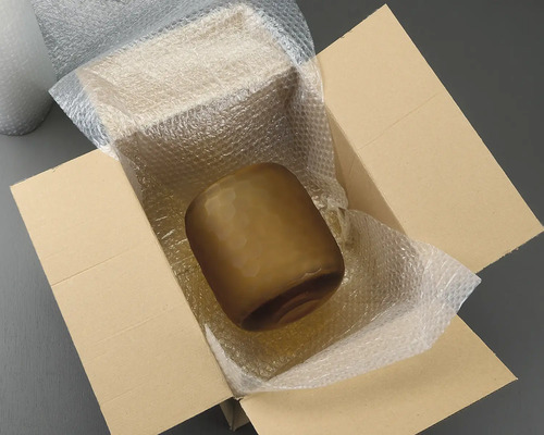 Braune Glasvase in einem Karton mit Luftpolsterfolie