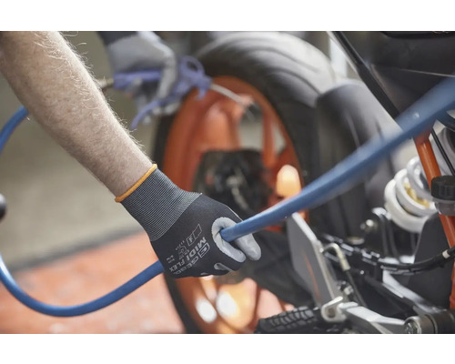 Une personne tenant un tuyau bleu avec une paire de gants de travail nettoie une moto.