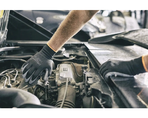 Une personne portant des gants de protection travaille sur un moteur de voiture.