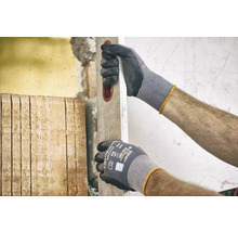 Mann mit Arbeitshandschuhen und Wasserwaage bei Renovierungsarbeiten.