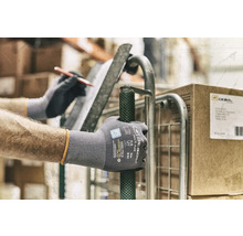 Eine Person mit Arbeitshandschuhen schiebt einen Rollwagen.