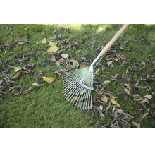 Râteau à feuilles avec manche en bois sur une pelouse avec des feuilles