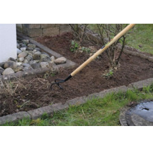 Gartenszene mit einem Sauzahn mit Holzgriff bei der Bodenbearbeitung