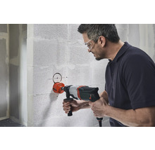 Un homme perce un trou dans un mur avec une scie cloche