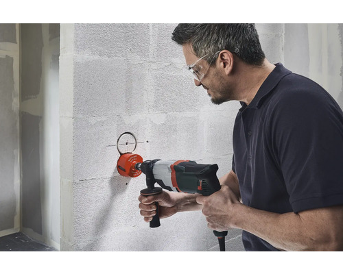 Un homme perce un trou dans un mur avec une scie cloche