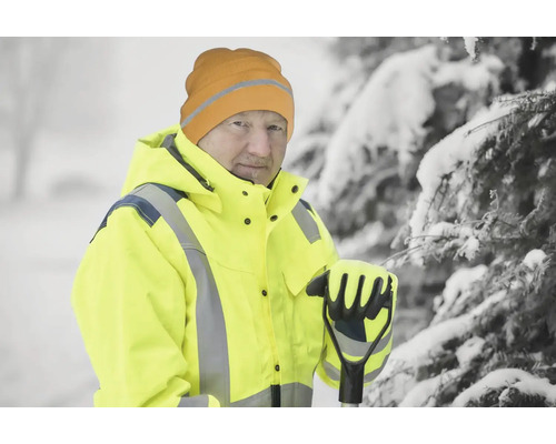 Homme avec veste jaune, bonnet et gants dans la neige avec râteau à feuilles