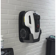 Wandmontierter Mähroboter an einer Backsteinmauer