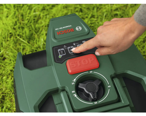 Gros plan d'un robot tondeuse Bosch avec une main touchant le panneau de commande, avec un bouton d'arrêt rouge et un bouton rotatif noir pour régler la hauteur de coupe.