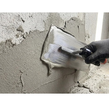 Une personne lisse du plâtre sur un mur avec une taloche.