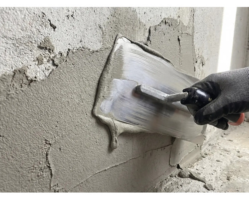Une personne lisse du plâtre sur un mur avec une taloche.