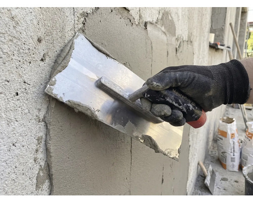 Handwerker glättet Putz mit einer Glättkelle an einer Wand.