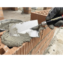 Maçon avec une truelle appliquant du mortier sur des briques pour la maçonnerie
