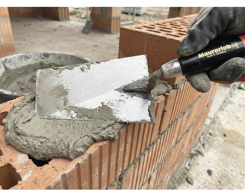 Maçon avec une truelle appliquant du mortier sur des briques pour la maçonnerie